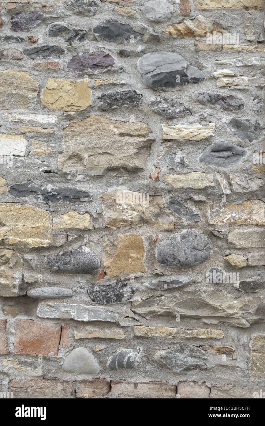 Alte Mauer aus unregelmässigen Steinen mit warmen Farben Stockfoto