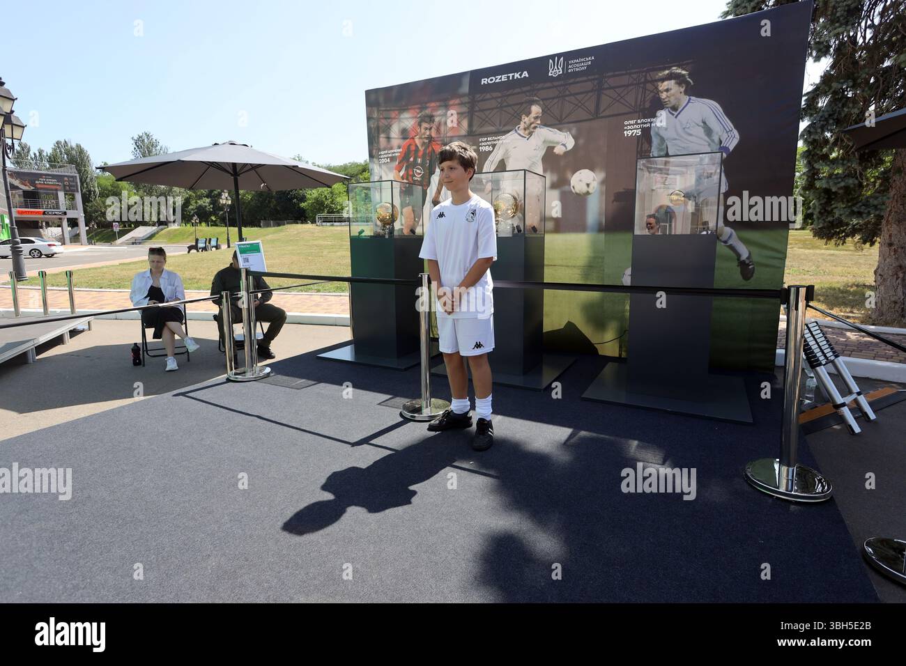 Junger Fußballspieler posiert für ein Foto vor den Goldenen Bälle im Taras Shevchenko Central Park of Culture and Leisure. Der Zweck der Veranstaltung ist die Beschaffung von Geldmitteln durch den Kauf von Souvenirs für das Kinderturnier „Schulball“ des ukrainischen Fußballverbandes. Der Ballon d’Or („Goldener Ball“) ist ein jährlicher Fußballpreis, der seit 1956 von der französischen Zeitschrift France Football verliehen wird, um den Spieler zu ehren, der in der vergangenen Saison die besten Leistungen gezeigt hat. Drei ukrainische Spieler haben diese Auszeichnung erhalten: OLEH Blokhin 1975, Ihor Bielanov 1986 und Andrii Schewtschenko 2004. Stockfoto