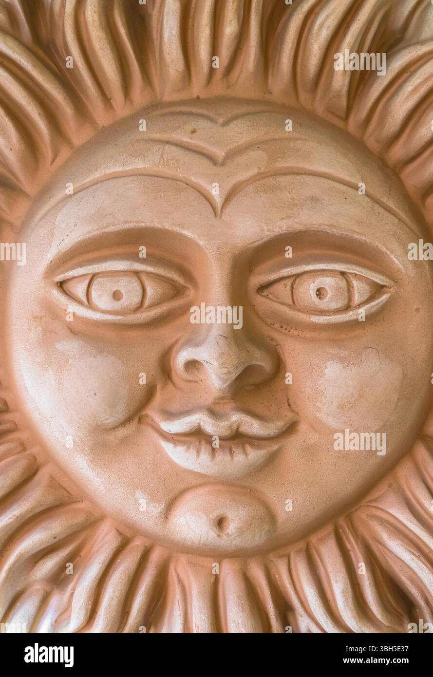 Tonskulptur, die eine lächelnde Sonne darstellt. Sie kann als Hintergrund verwendet werden Stockfoto