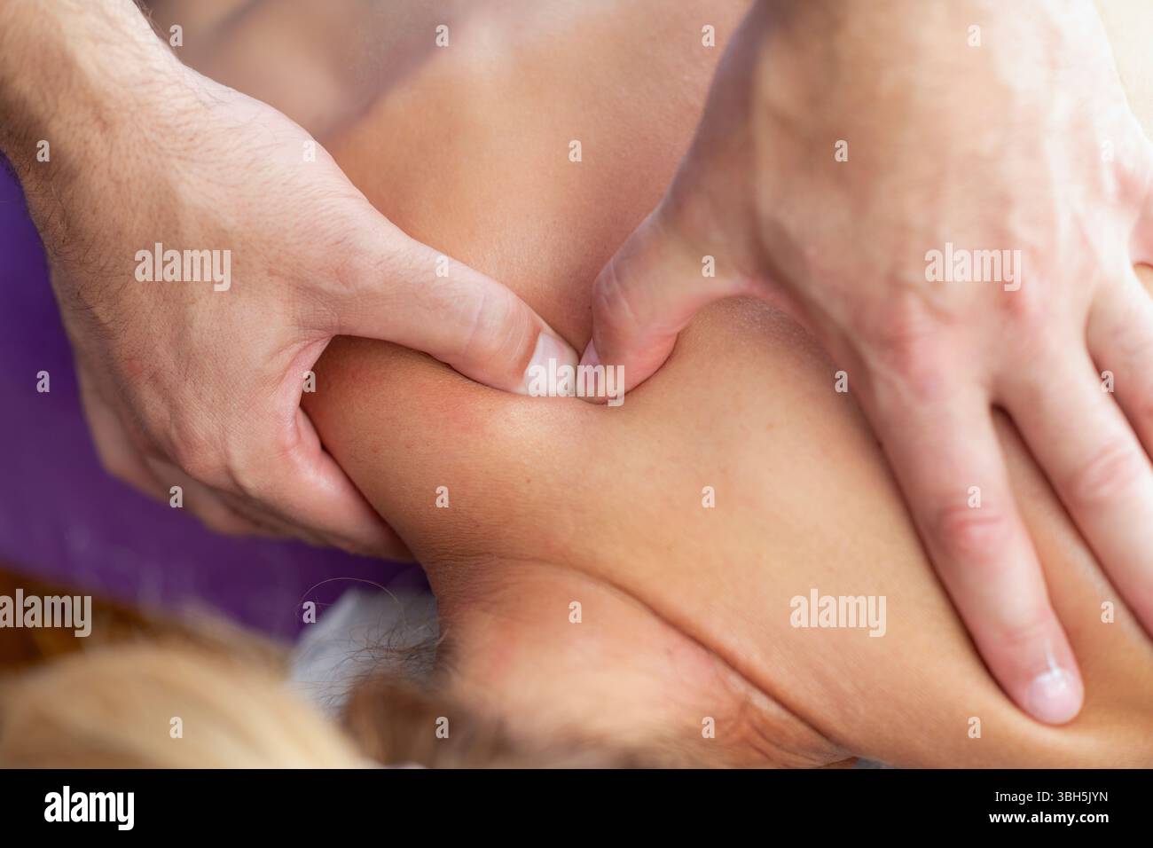 Der Physiotherapeut führt eine Tiefenmassage an der Schulter des Patienten durch, um Muskelverspannungen zu lösen und die Mobilität in einer therapeutischen Umgebung zu verbessern. Stockfoto
