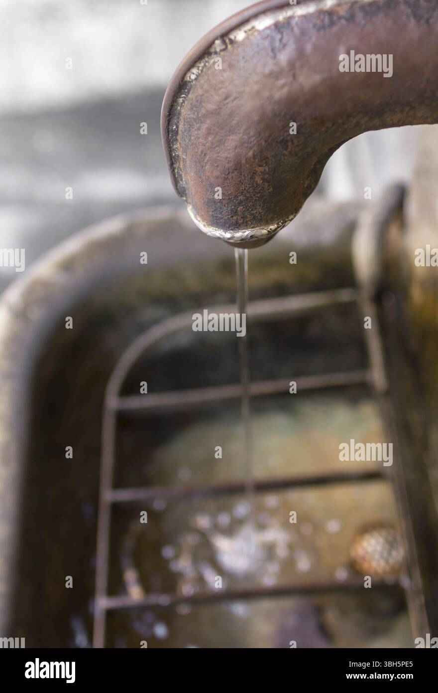 Details eines öffentlichen italienischen Springbrunnens mit rostigem Auslauf. Mittelalterliche Zeit. Cooles Bokeh Stockfoto