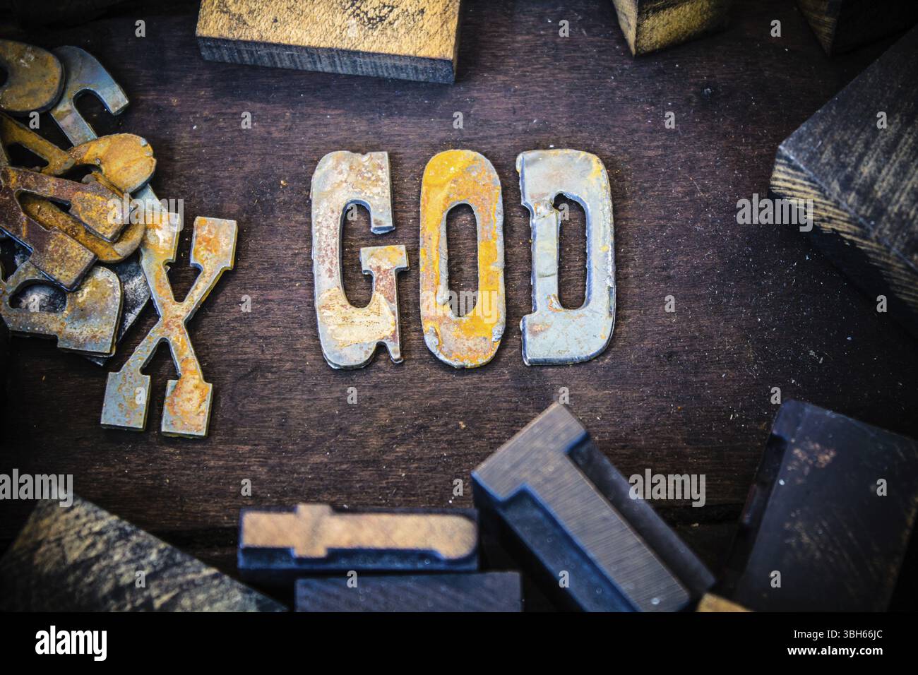 Das Wort GOTT in rostigen Metallbuchstaben, umgeben von Vintage-Holz- und Metall-Buchdruck Stockfoto
