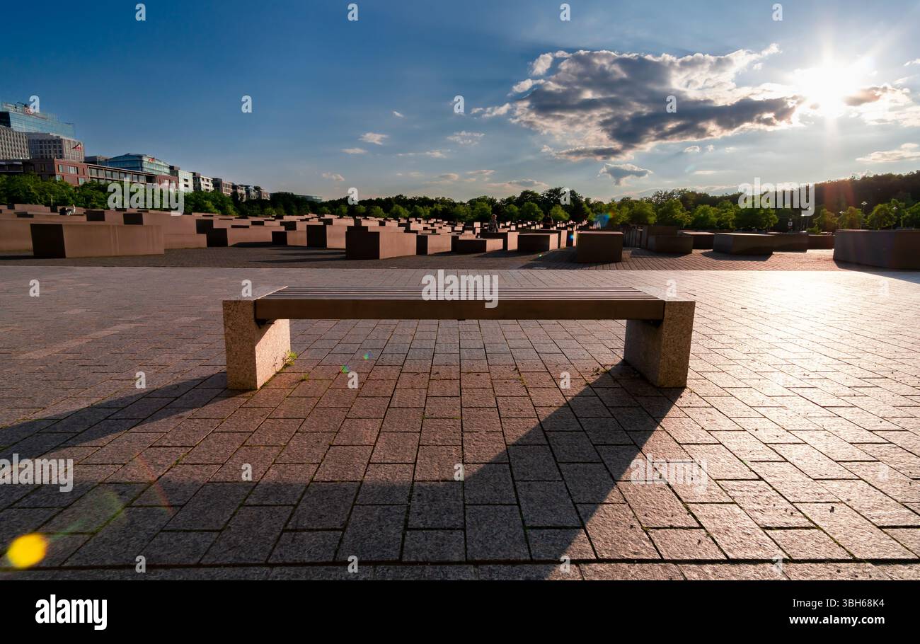 Abendlicht am Holocaust-Denkmal in Berlin, mit einer Bank im Vordergrund und Betonblöcken im Hintergrund, Deutschland. Stockfoto