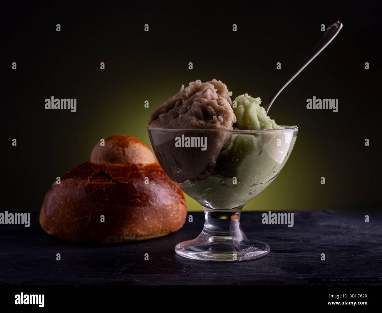 Handwerkliche sizilianische Granita, möglicherweise Pistazien- und Haselnussaromen, serviert mit einer traditionellen Brioche. Ein gefrorenes Gourmet-Dessert mit Dramat Stockfoto