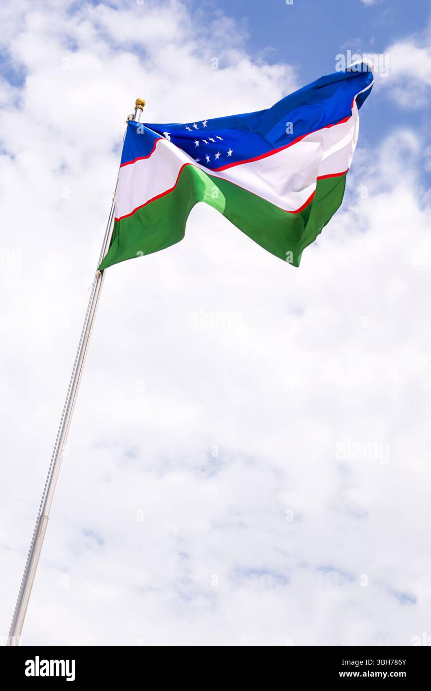 Nationalflagge von Usbekistan flattert in der Brise mit bewölktem Himmel Hintergrund Stockfoto