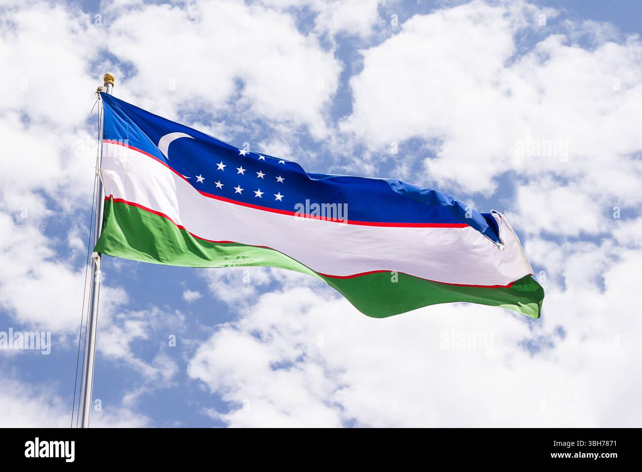 Nationalflagge von Usbekistan flattert in der Brise mit bewölktem Himmel Hintergrund Stockfoto