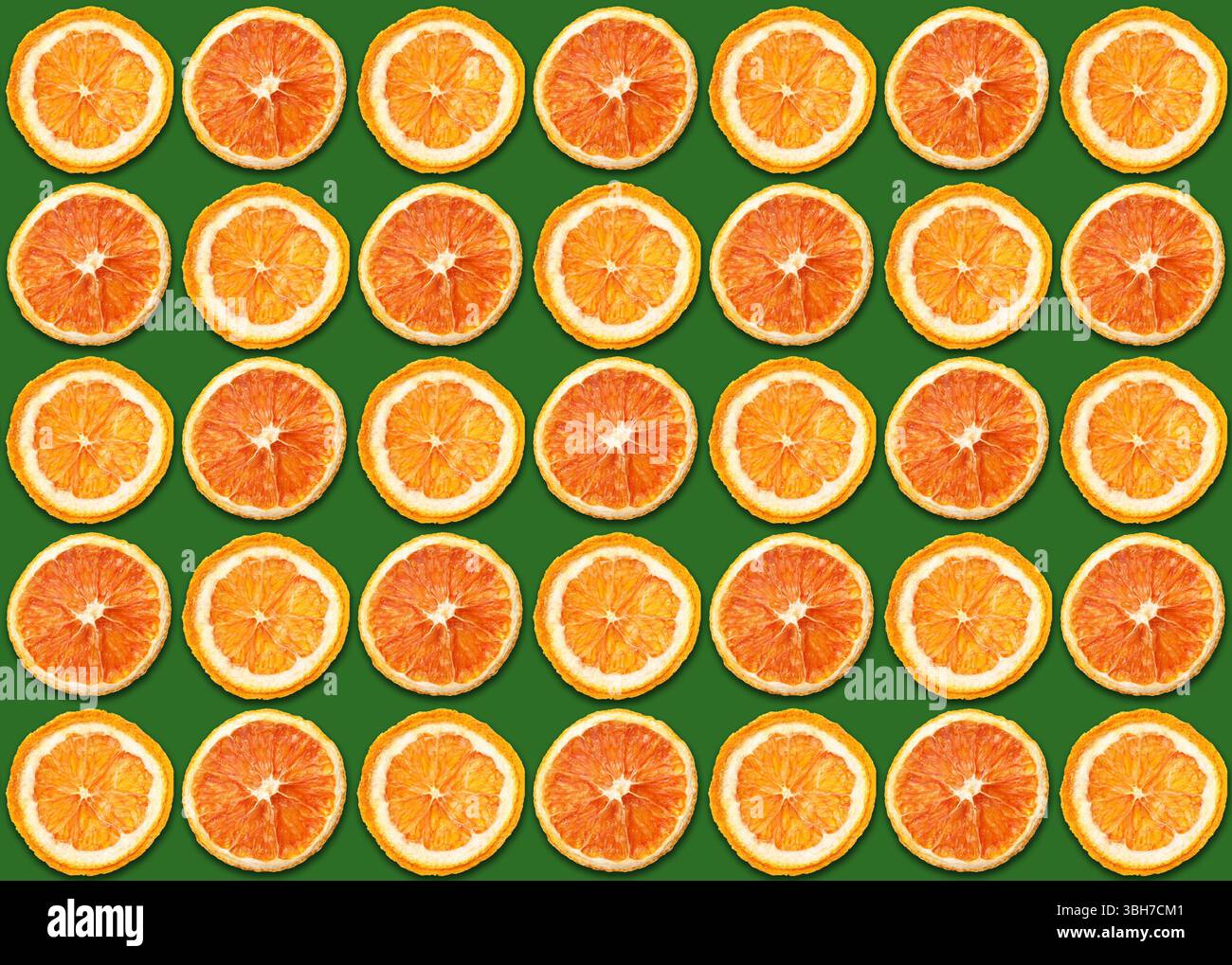In Scheiben geschnittenes orangefarbenes Muster. Helle saftige Zitrusscheiben auf grünem Hintergrund. Farbenfrohe symmetrische Komposition. Frische Vitaminfrucht-Textur für Sommerdesign. Stockfoto