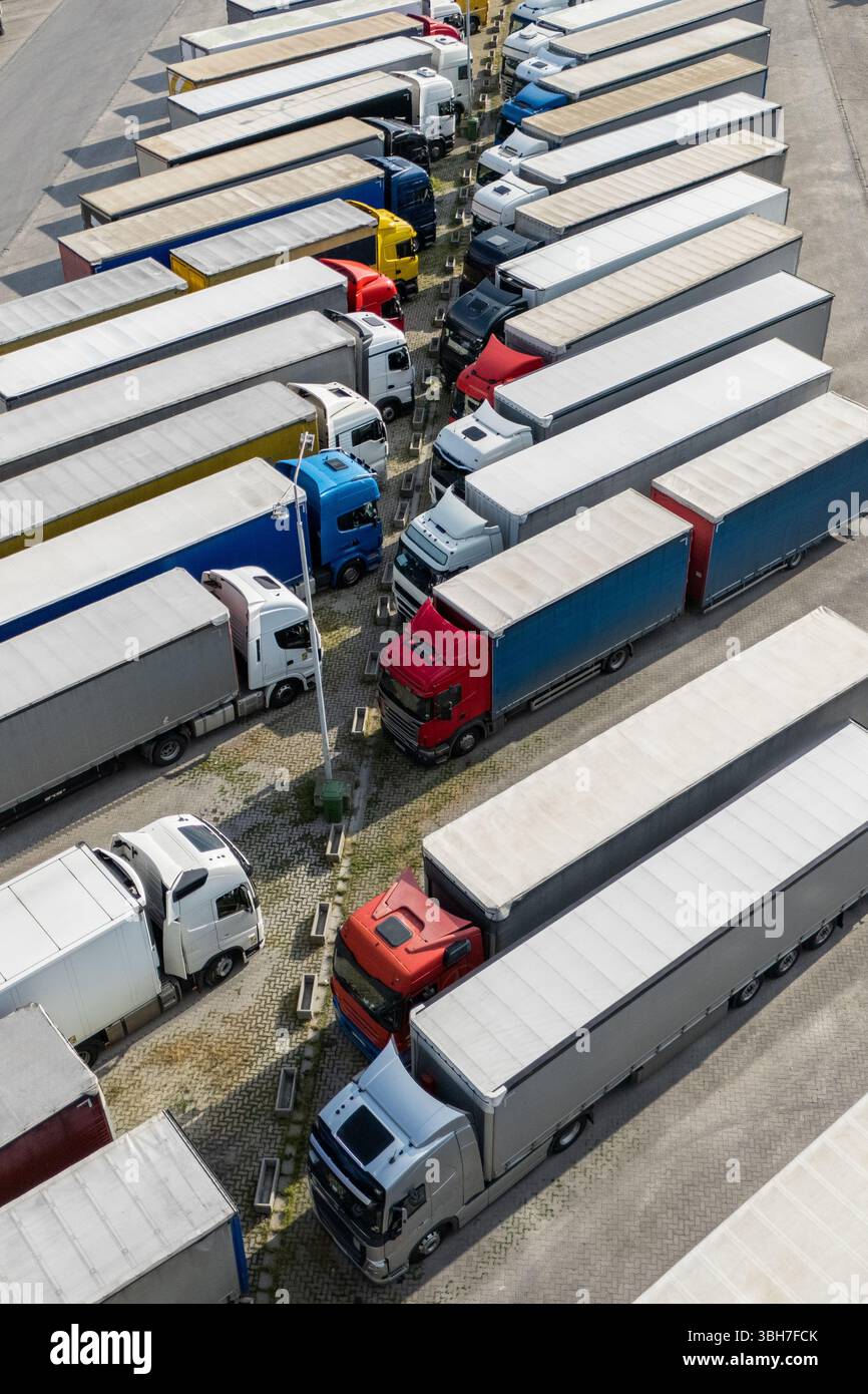 Aus der Vogelperspektive eines großen LKW-Parkplatzes an einem Logistikzentrum mit mehreren gewerblichen Sattelzügen, die in organisierten Reihen geparkt sind. Stockfoto