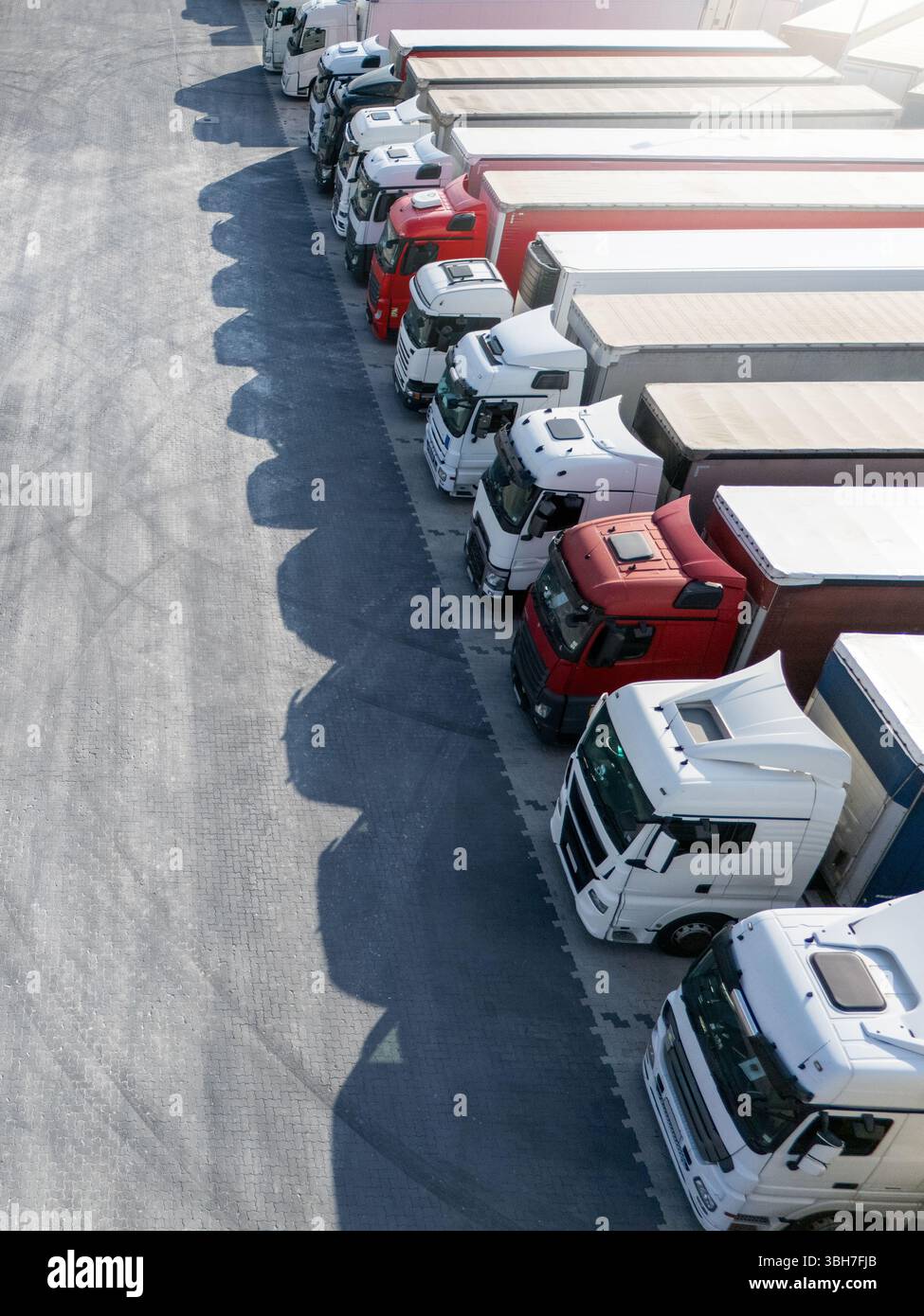 Aus der Vogelperspektive eines großen LKW-Parkplatzes an einem Logistikzentrum mit mehreren gewerblichen Sattelzügen, die in organisierten Reihen geparkt sind. Stockfoto