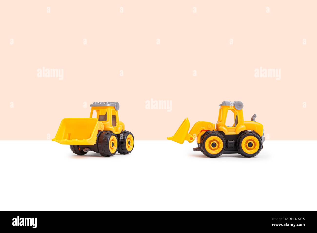 Gelbe Planierraupe mit schwarzen Rädern und grauen Dächern, perfekt für Kinder oder Lernspielzeug auf beigefarbenem Hintergrund. Ideal für den Einsatz in e Stockfoto