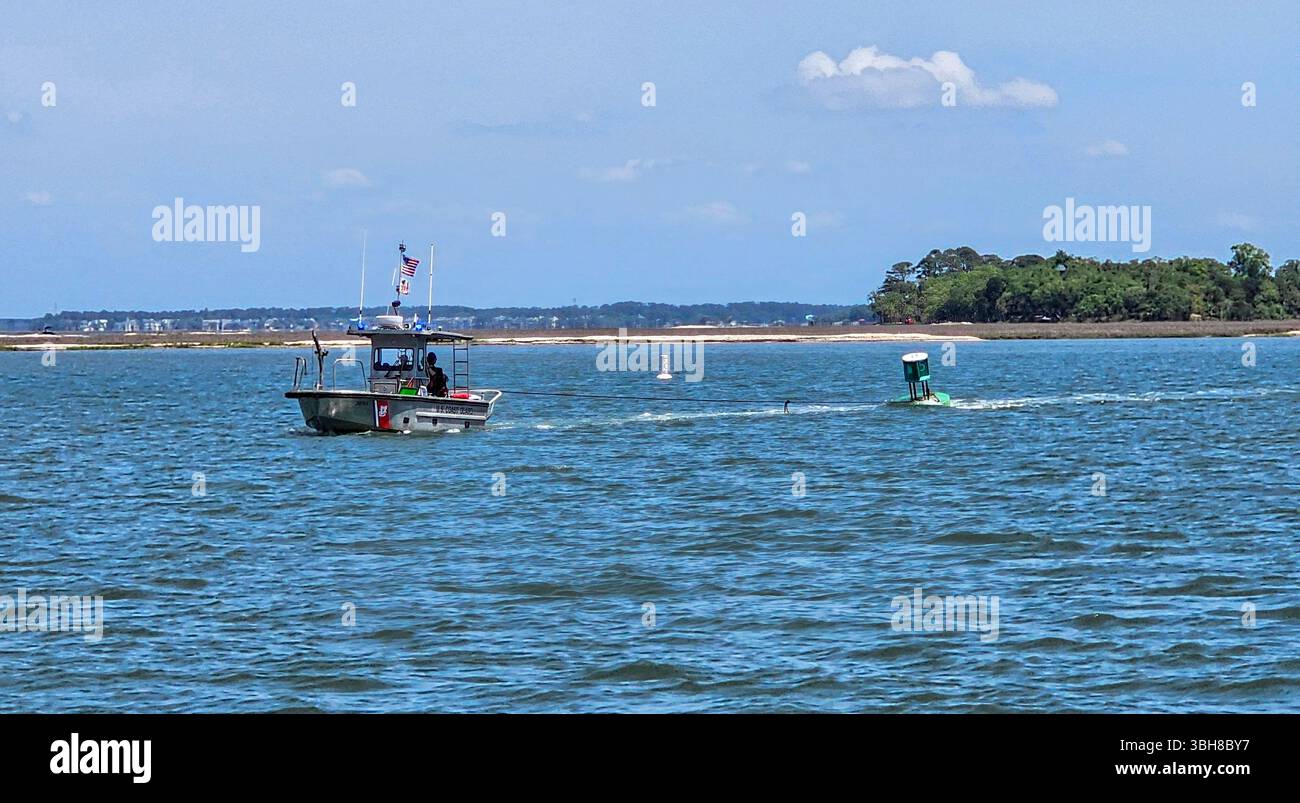 Die US-Küstenwache zieht ein grünes schwimmendes ATON in der Nähe von Harbour Town, Hilton Head Island, South Carolina. - Smartphone-aufgenommenes Stockfoto