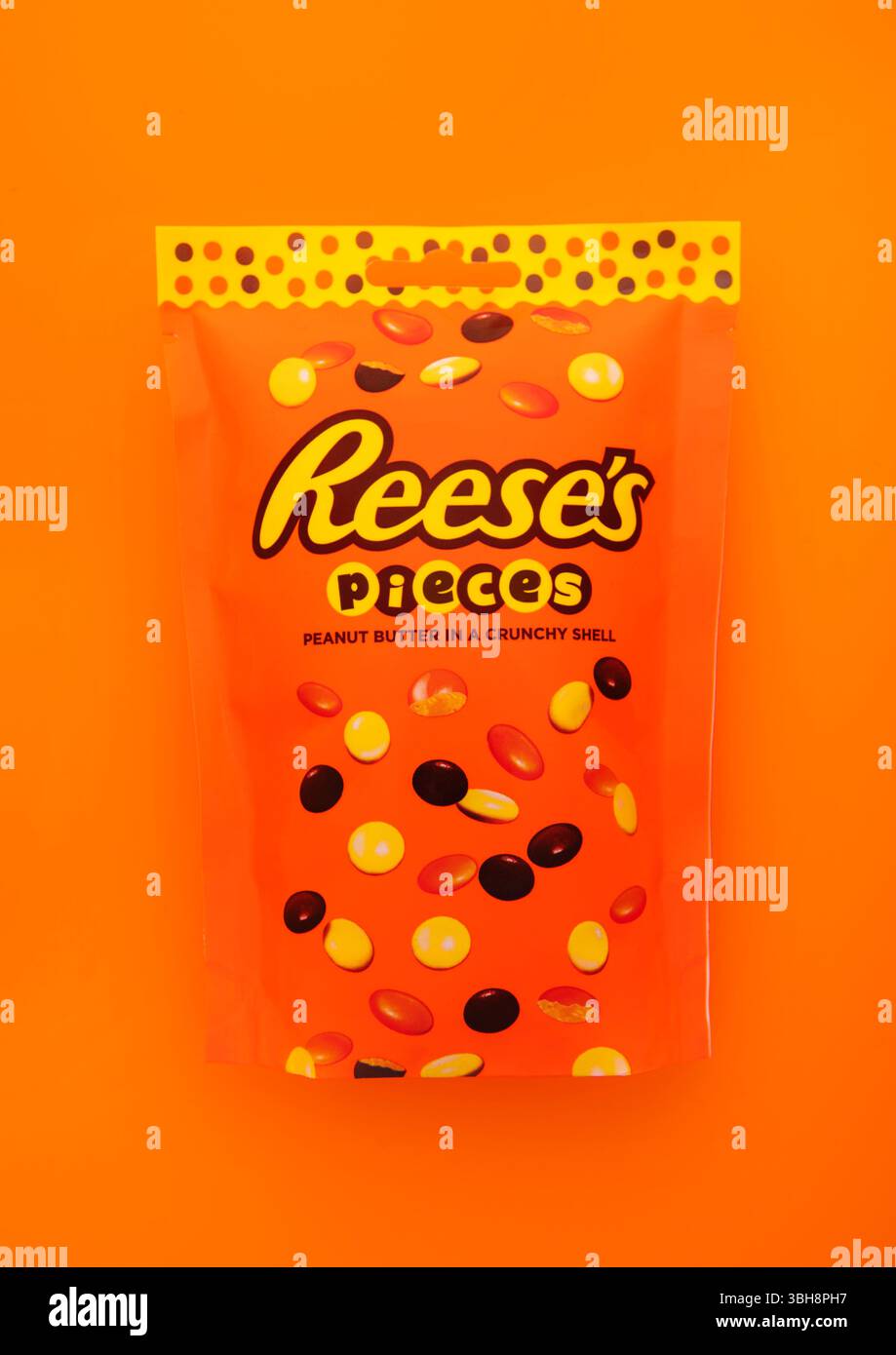 LONDON, UK - 11. JANUAR 2025: Reese's Stücke Erdnussbutter in knuspriger Schale auf orangefarbenem Hintergrund. Stockfoto