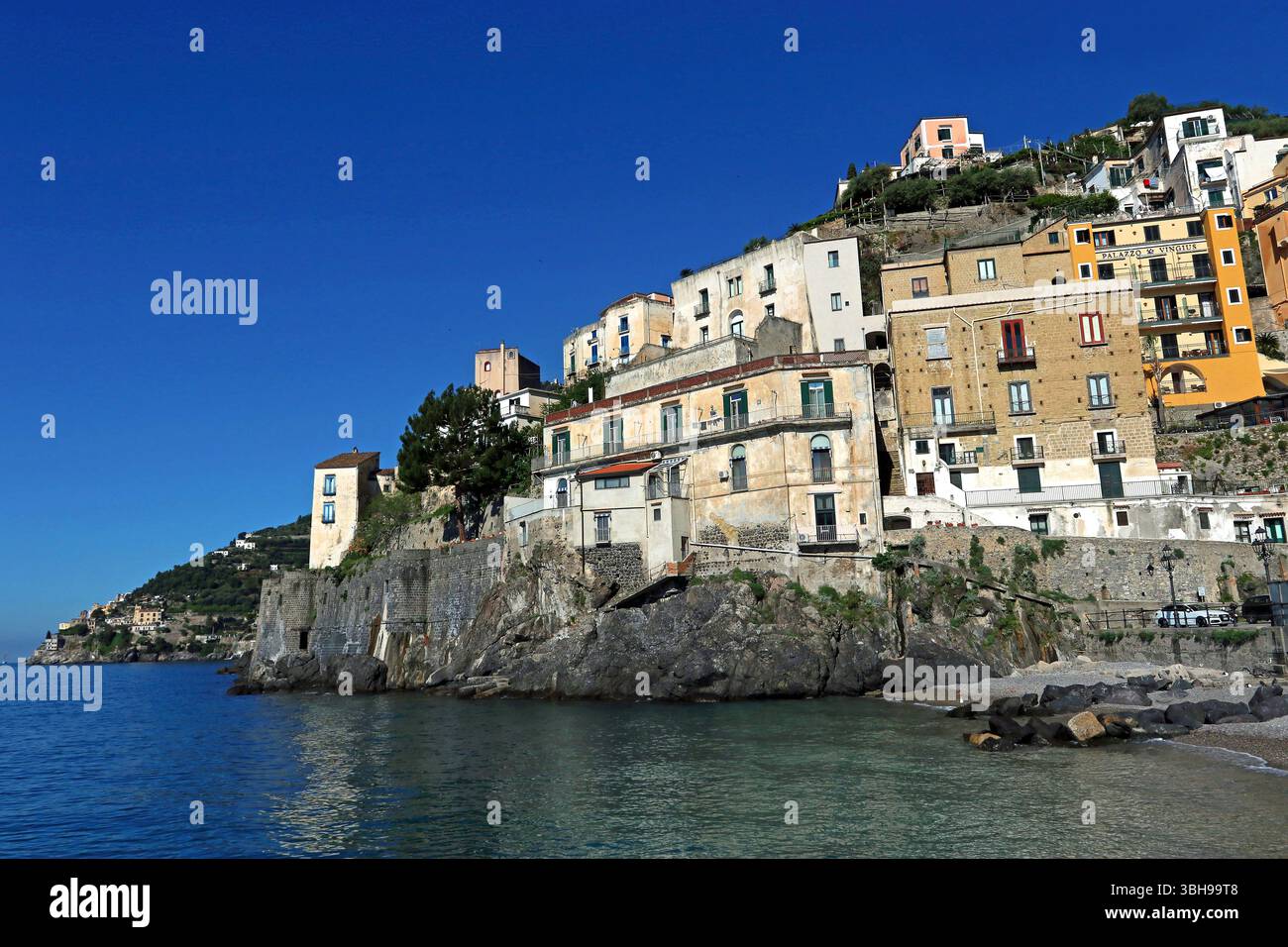 In Minori, einer kleinen Stadt an der Amalfiküste, erheben sich pastellfarbene Häuser über dem Strand und kurvenförmig um die Küste herum Stockfoto