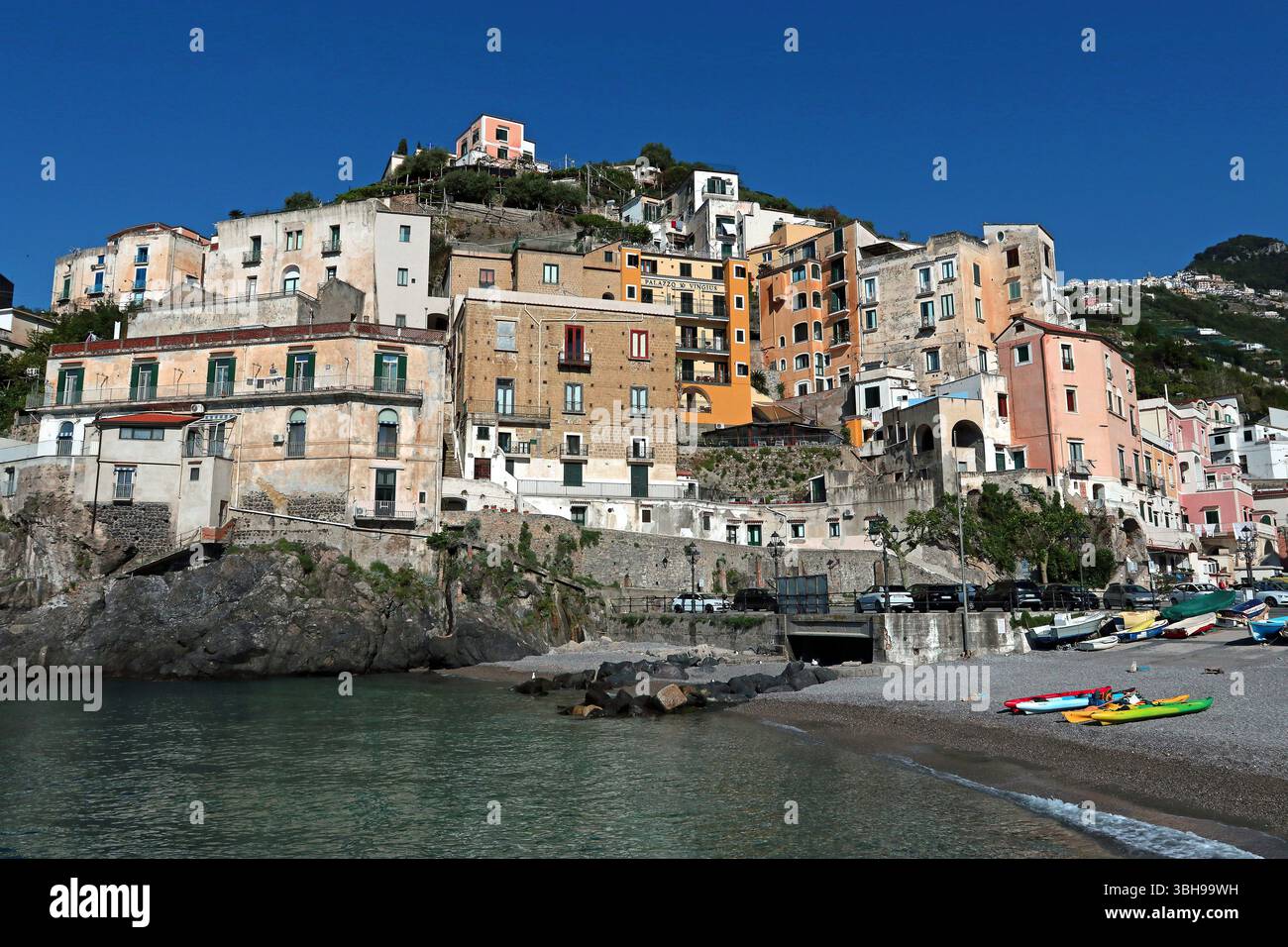 In Minori, einer kleinen Stadt an der Amalfiküste, erheben sich pastellfarbene Häuser über dem Strand und kurvenförmig um die Küste herum Stockfoto