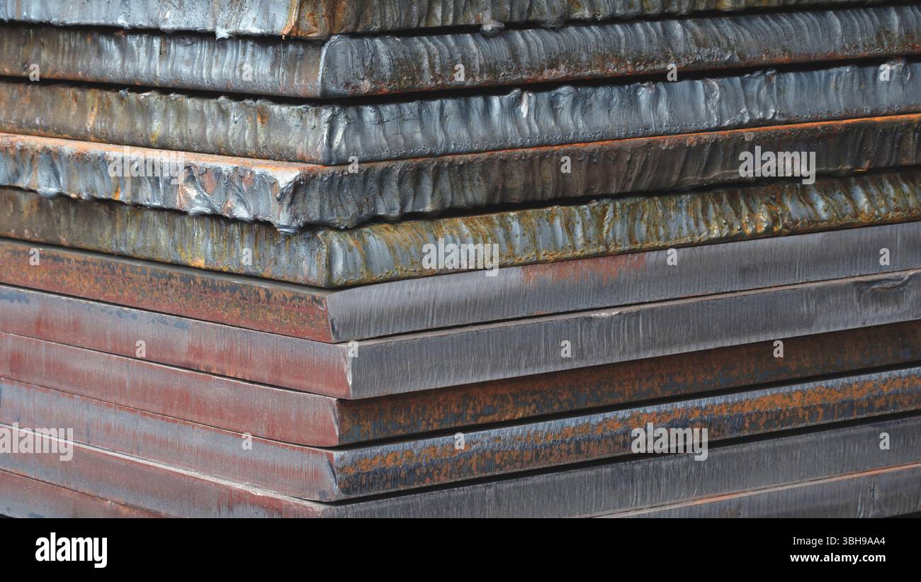 Stapel dicker Schwermetallplatten mit rostiger und unebener Oberfläche nach dem Laserschneiden. Die Platten werden übereinander gestapelt, wodurch ein Gefühl der Tiefe entsteht Stockfoto