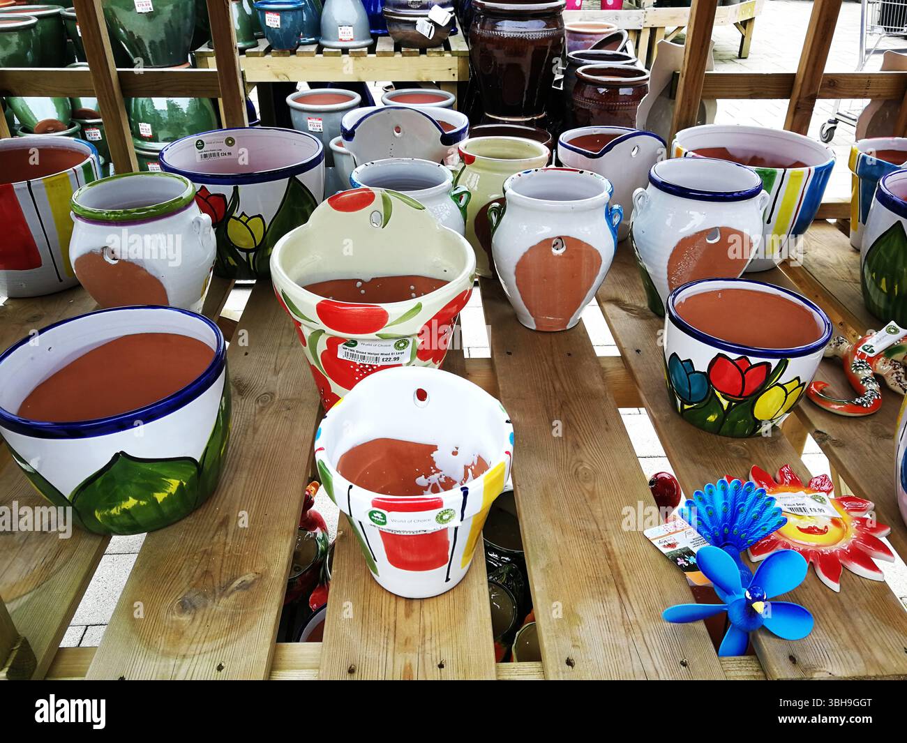 Bunte dekorative Keramiktöpfe auf Holzregalen im Garden Store. Snowhill, Großbritannien Stockfoto