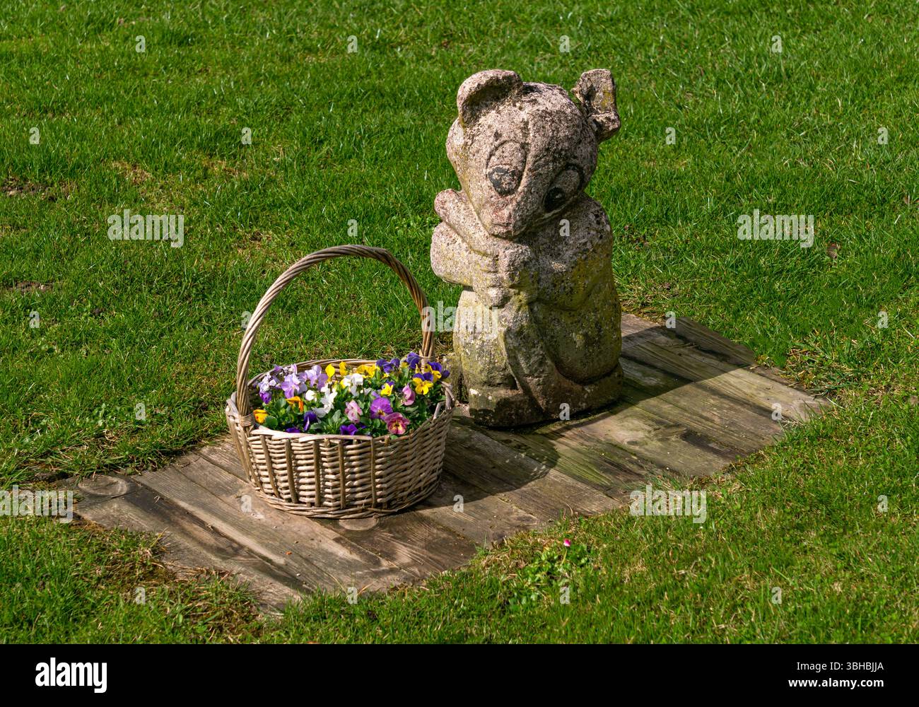 Die Komposition einer Steinfigur und eines Blumenkörbes. Stockfoto