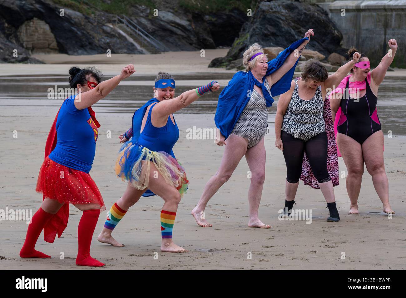 Die Teilnehmer treffen sich am Strand von Towan und bereiten sich auf die jährliche Veranstaltung „Superhero in the Cold“ vor, um Spenden für die britische Krebsforschung zu sammeln. Stockfoto