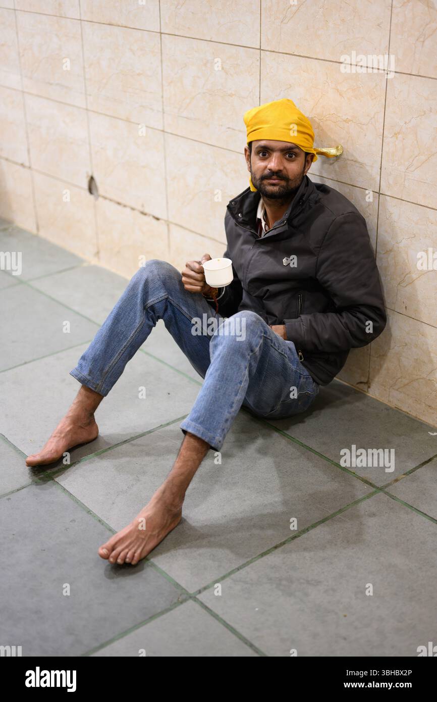 Delhi, Indien – 21. Februar 2025: Sikh-Mann sitzt auf dem Boden und trinkt Marsala Chai Tee im Gurudwara Bangla Sahib Sikh Tempel in Delhi Stockfoto