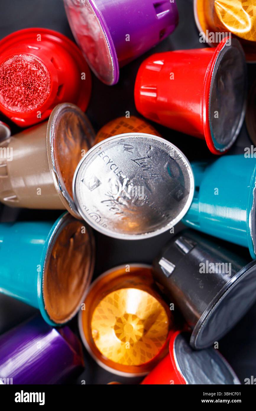 Eine Sammlung von verschiedenen farbenfrohen Kaffeekapseln oder -Schoten auf einem strukturierten grauen Hintergrund, in einer verstreuten Form angeordnet Stockfoto