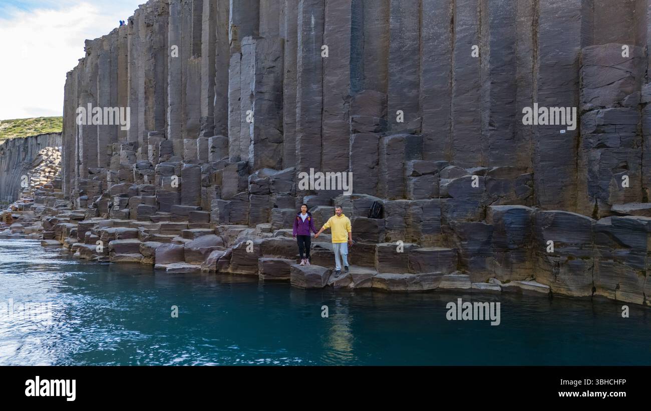 Besucher bestaunen die atemberaubenden Basaltsäulen und das türkisfarbene Wasser des Studlagil Canyon in Island. Stockfoto