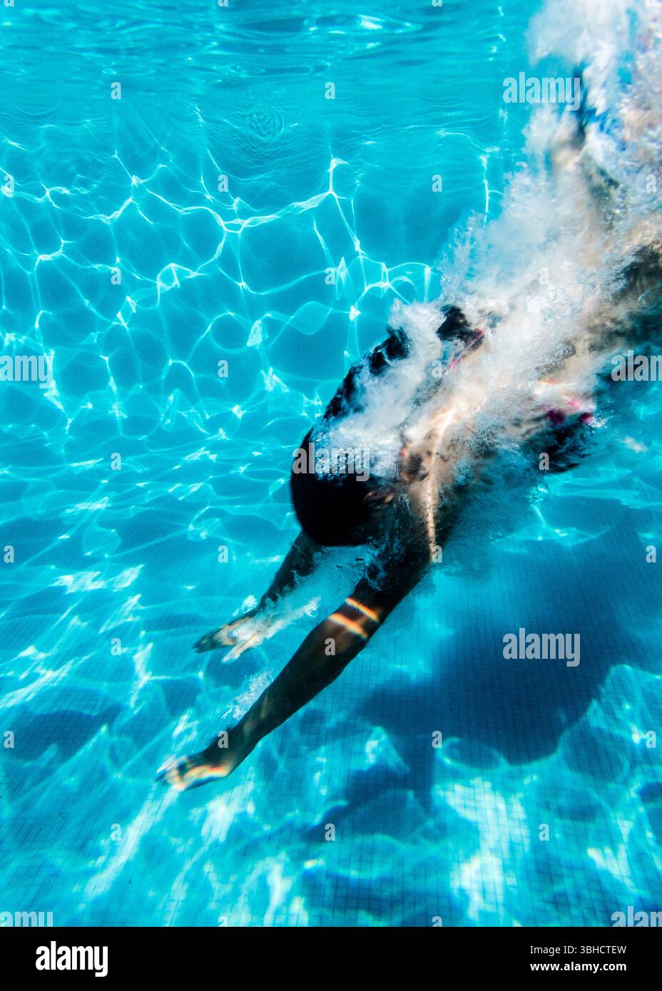 Eine Person ist in einen Pool getaucht und schwimmt nach unten. Stockfoto
