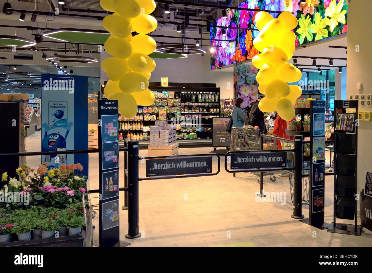 Edeka Supermarkt, Neueröffnung. Die Edeka-Gruppe, ehemals Abkürzung für Einkaufsgenossenschaft der Kolonialwarenhändler im Halleschen Torbezirk zu Berlin, ist ein genossenschaftlich organisierter kooperativer Unternehmensverbund im deutschen Einzelhandel. Edeka betreibt mit Edeka Fruchtkontor eine eigene Beschaffungsorganisation vorrangig für Obst- und Gemüseimporte *** Edeka Supermarket, Neueröffnung die Edeka Group, ehemals eine Abkürzung für Einkaufsgenossenschaft der Kolonialwarenhändler im Halleschen Torbezirk zu Berlin, ist eine genossenschaftlich organisierte Unternehmensgruppe im deutschen Retai Stockfoto