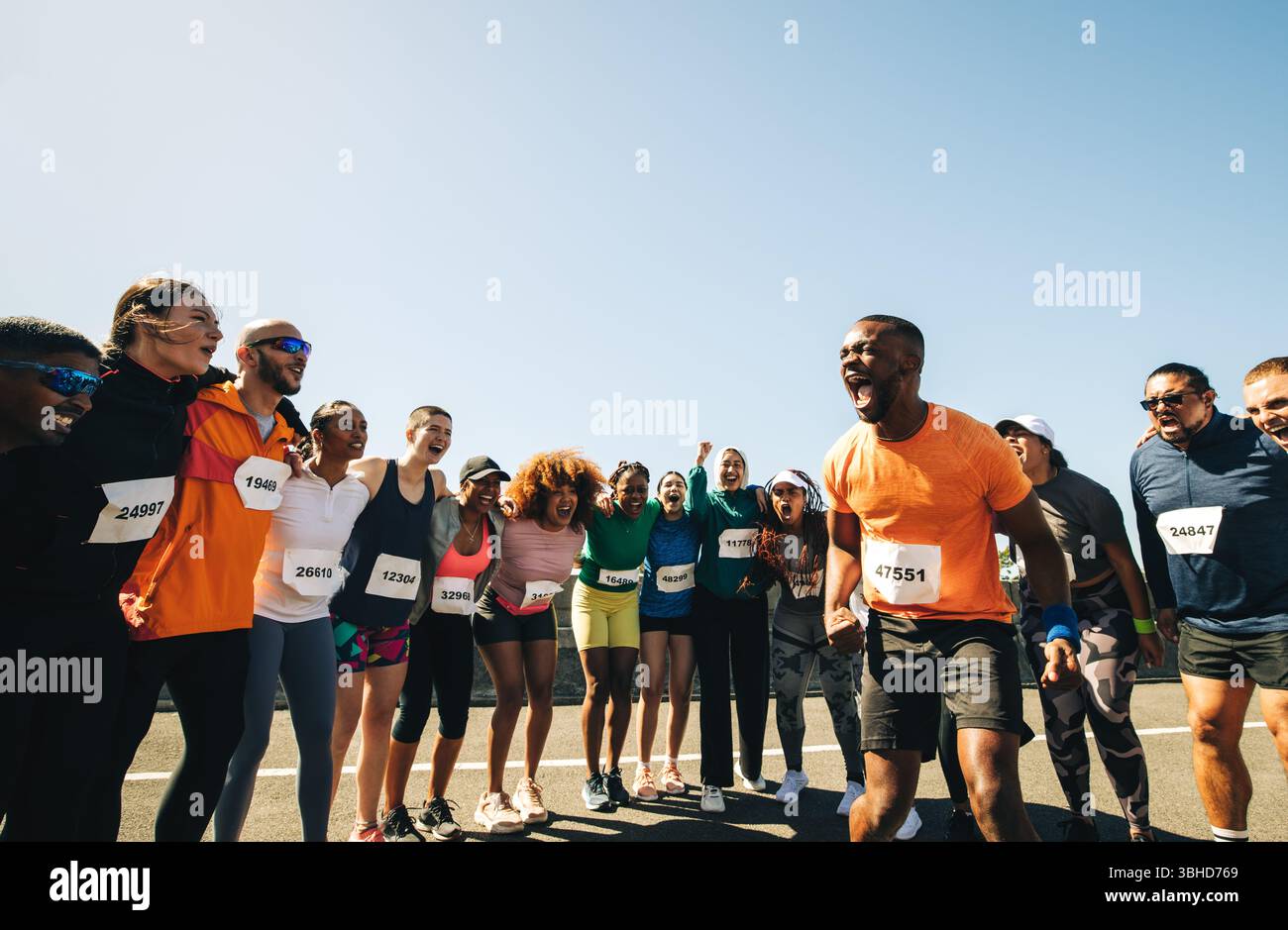 Eine vielfältige Gruppe begeisterter Läufer wird vor der Teilnahme an einem Marathon kräftig angefeuert. Perfekte Bedingungen für das Rennen Stockfoto