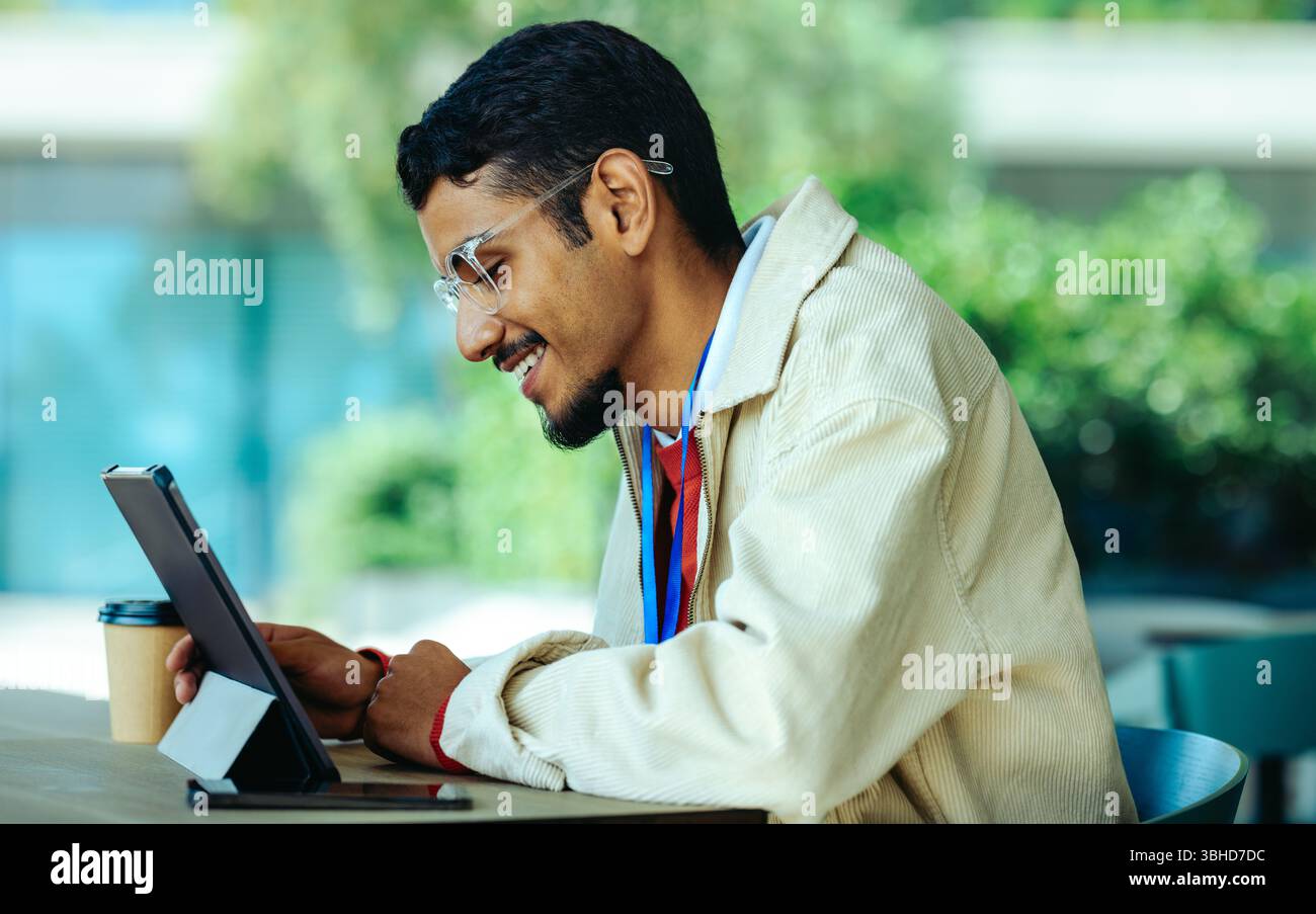 Ein Softwareentwickler arbeitet im Freien produktiv und konzentriert sich dabei auf ein digitales Gerät. Das Unternehmensumfeld wird durch ein entspannendes s ergänzt Stockfoto