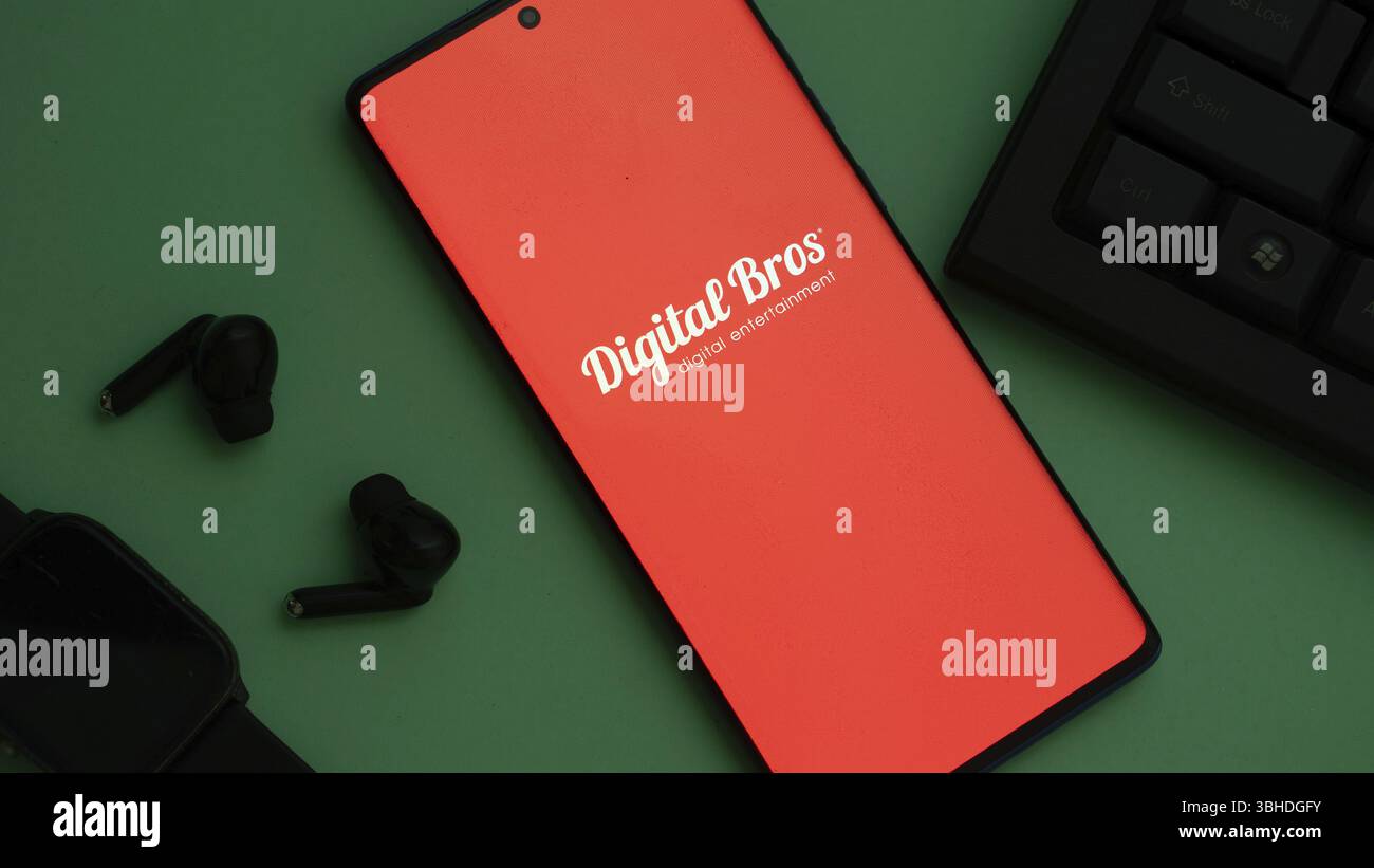 Smartphone mit Digital Bros Logo und Ohrhörern auf grüner Oberfläche, roter Bildschirm Stockfoto