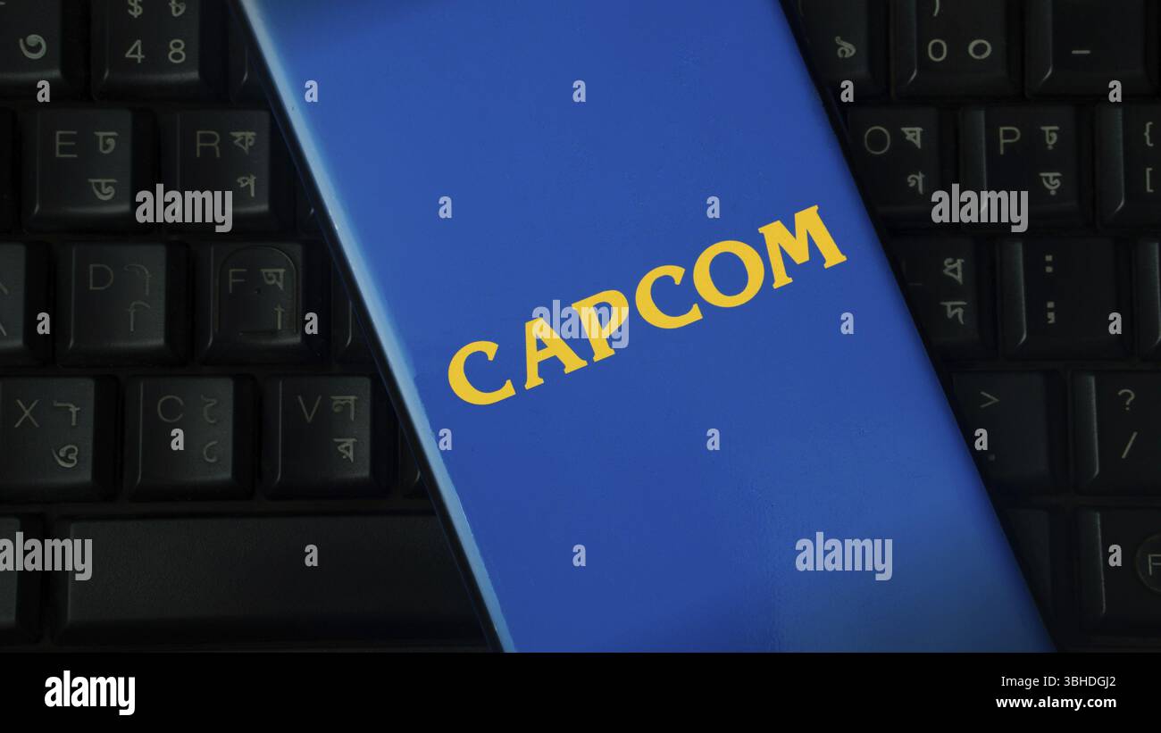 Gelbes Capcom-Logo auf blauem Hintergrund, das eine schwarze Tastatur überlagert Stockfoto