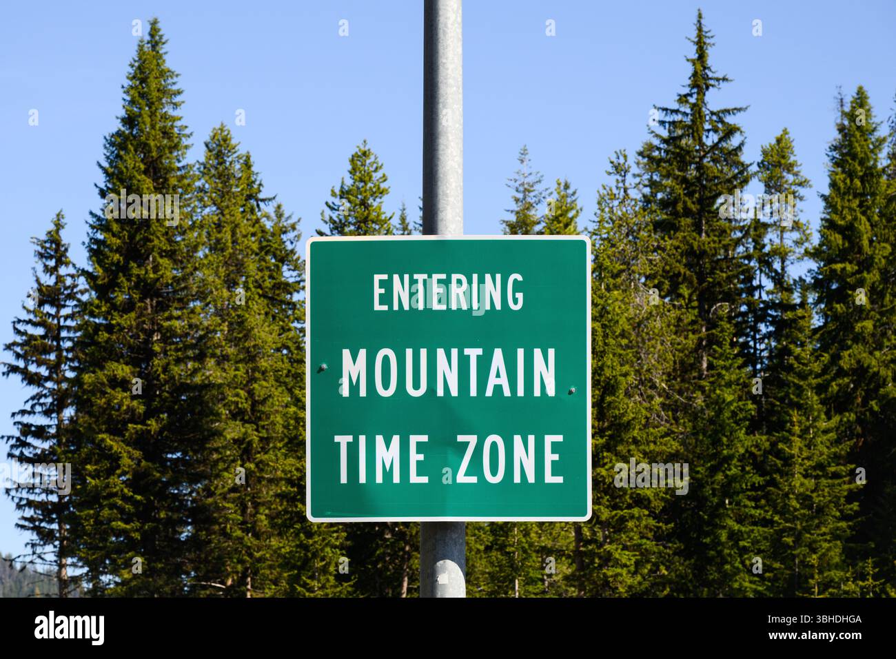 Schild für ländliche Gebiete mit weißem Text auf grünem Grün, das in die Mountain Time Zone eingeht Stockfoto