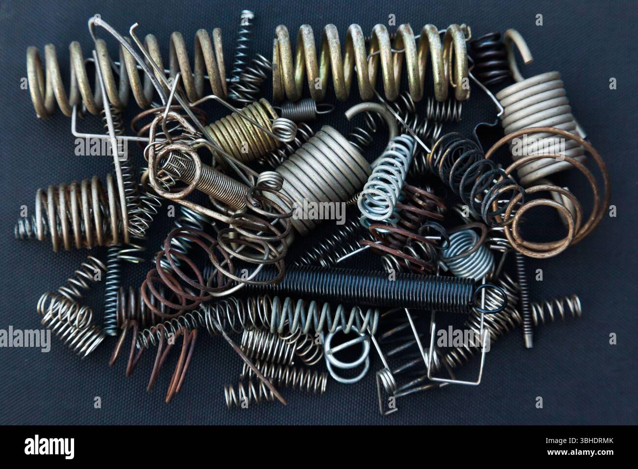 Viele kleine Federn unterschiedlicher Größe liegen auf einem Haufen vor schwarzem Hintergrund. Stockfoto