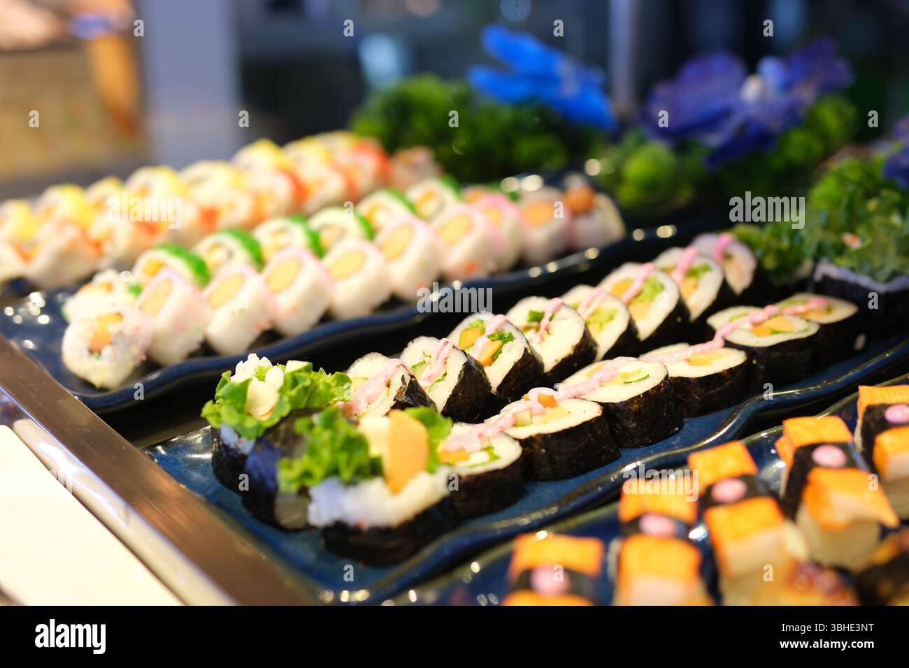Vielfalt an farbenfrohen Sushi-Brötchen, kunstvoll mit Gurkenscheiben und Thunfisch-Sashimi arrangiert. Hochwertige 4K-Aufnahmen Stockfoto