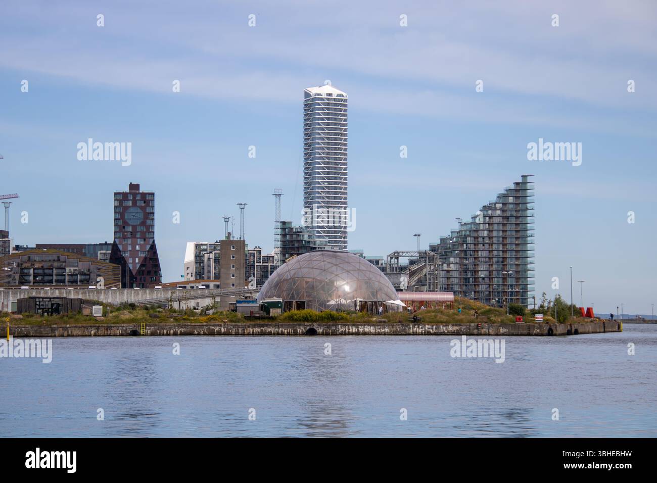 Aarhus, Dänemark: Leuchtturm „Bugten Fyr“ vor Skyline von Aarhus Ø mit Wohnkomplex „Isbjerget“ und Hochhaus „Light*House“ am Wasser Stockfoto