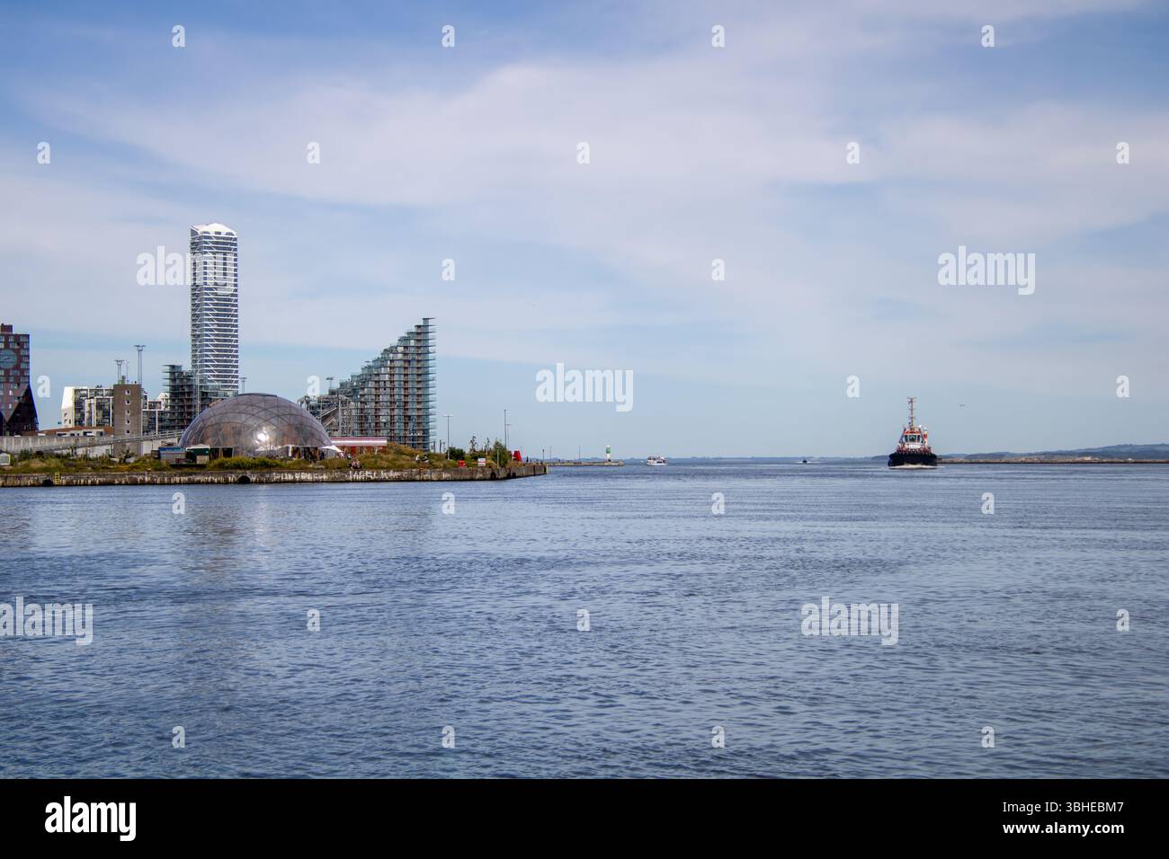 Aarhus, Dänemark: Leuchtturm „Bugten Fyr“ vor Skyline von Aarhus Ø mit Wohnkomplex „Isbjerget“ und Hochhaus „Light*House“ am Wasser Stockfoto