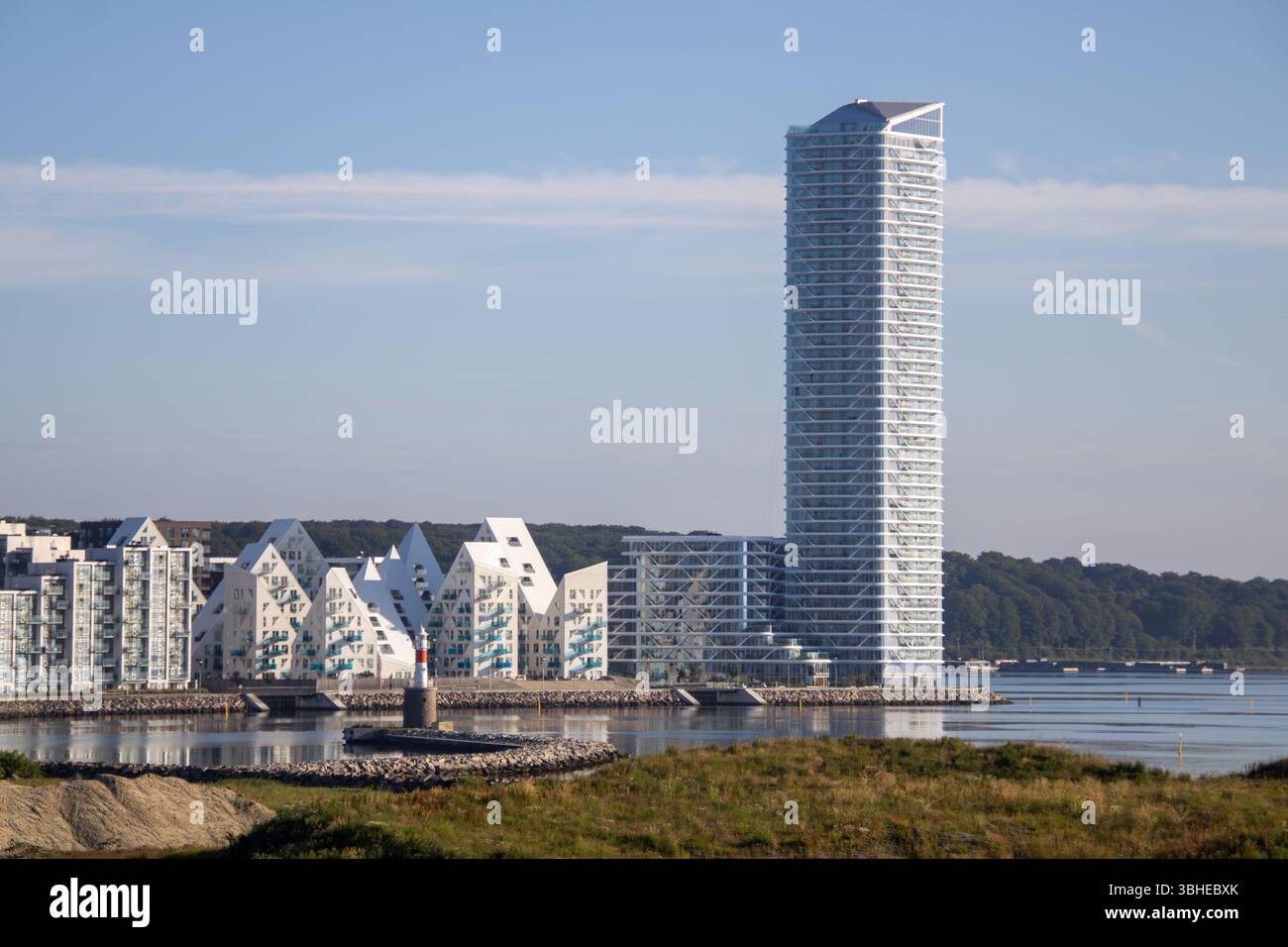 Aarhus, Dänemark: Leuchtturm „Bugten Fyr“ vor Skyline von Aarhus Ø mit Wohnkomplex „Isbjerget“ und Hochhaus „Light*House“ am Wasser Stockfoto