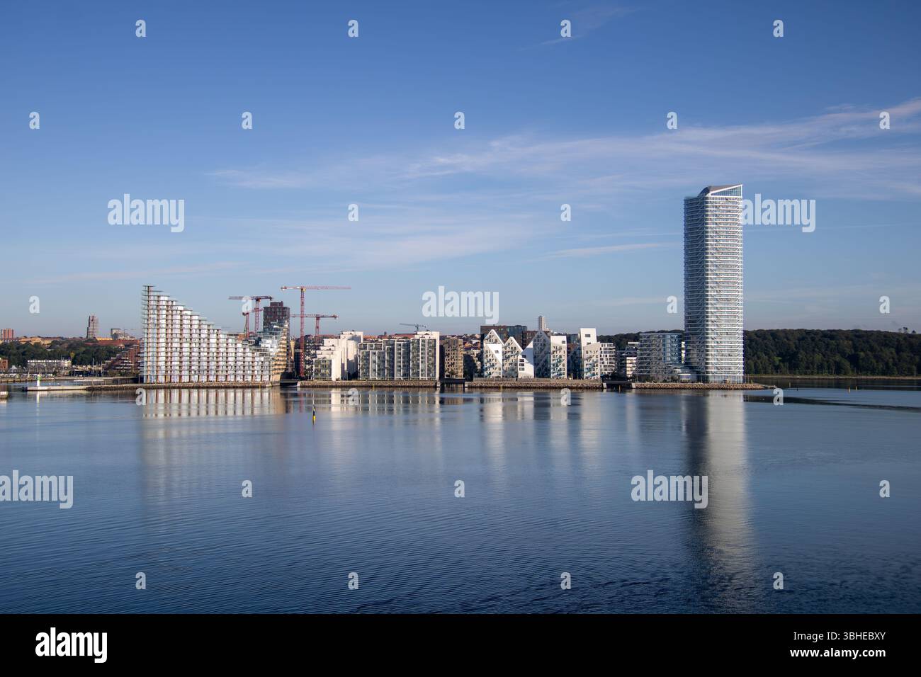 Aarhus, Dänemark: Leuchtturm „Bugten Fyr“ vor Skyline von Aarhus Ø mit Wohnkomplex „Isbjerget“ und Hochhaus „Light*House“ am Wasser Stockfoto