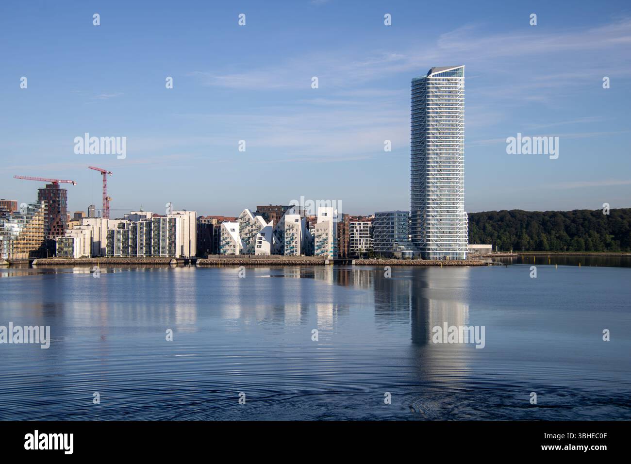 Aarhus, Dänemark: Leuchtturm „Bugten Fyr“ vor Skyline von Aarhus Ø mit Wohnkomplex „Isbjerget“ und Hochhaus „Light*House“ am Wasser Stockfoto