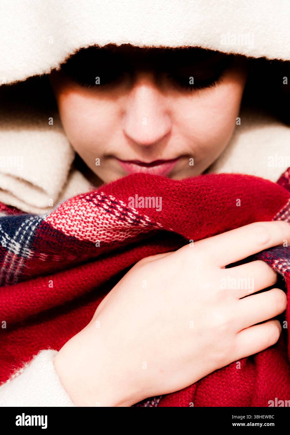 Ein leicht niederwinkliges Nahporträt eines jungen Menschen mit heller Haut. Sie tragen ein cremefarbenes Kapuzenkleid und ein Rot, weiß und Blau. Stockfoto Ein leicht niederwinkliges Nahporträt eines jungen Menschen mit heller Haut. Sie tragen ein cremefarbenes Kapuzenkleid und ein Rot, weiß und Blau. Stockfoto