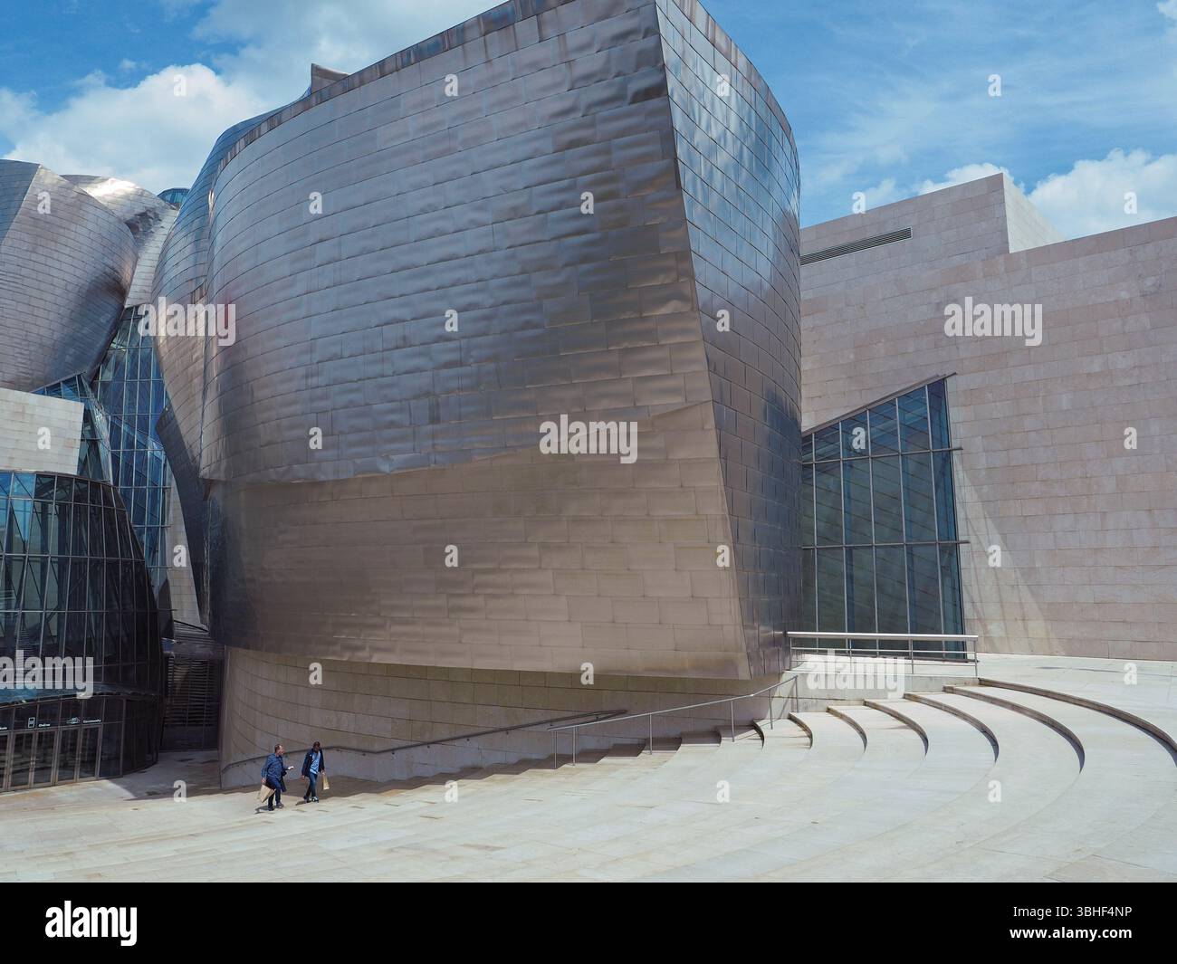 Architektur des titanverkleideten Guggenheim Museums in Bilbao, Spanien, mit 2 Besuchern im Maßstab. Stockfoto