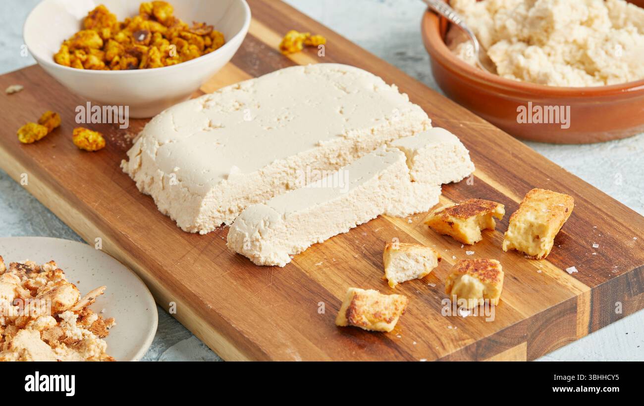 Hausgemachter veganer Paneer auf Holzbrett – eine pflanzliche Milchalternative, perfekt für sauberes Essen, für die Zubereitung von Mahlzeiten, veganes Kochen oder für Fotoaufnahmen Stockfoto