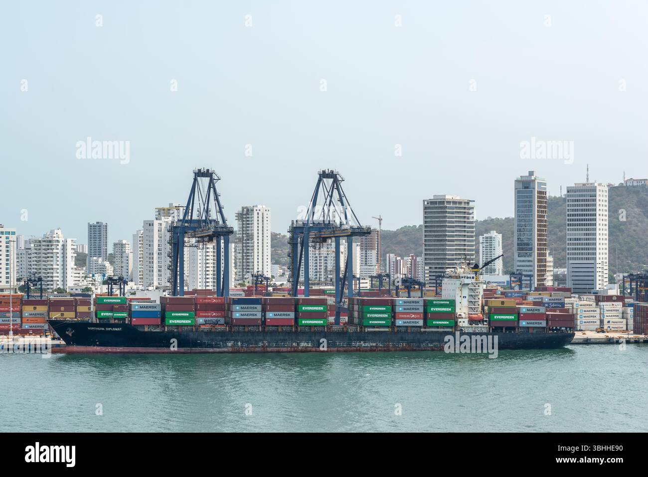 Cartagena, Kolumbien - 12. April 2024: Die Hafenszene zeigt das Containerschiff Northern Diplomat, Kräne und Container, mit Cartagenas Größe Stockfoto