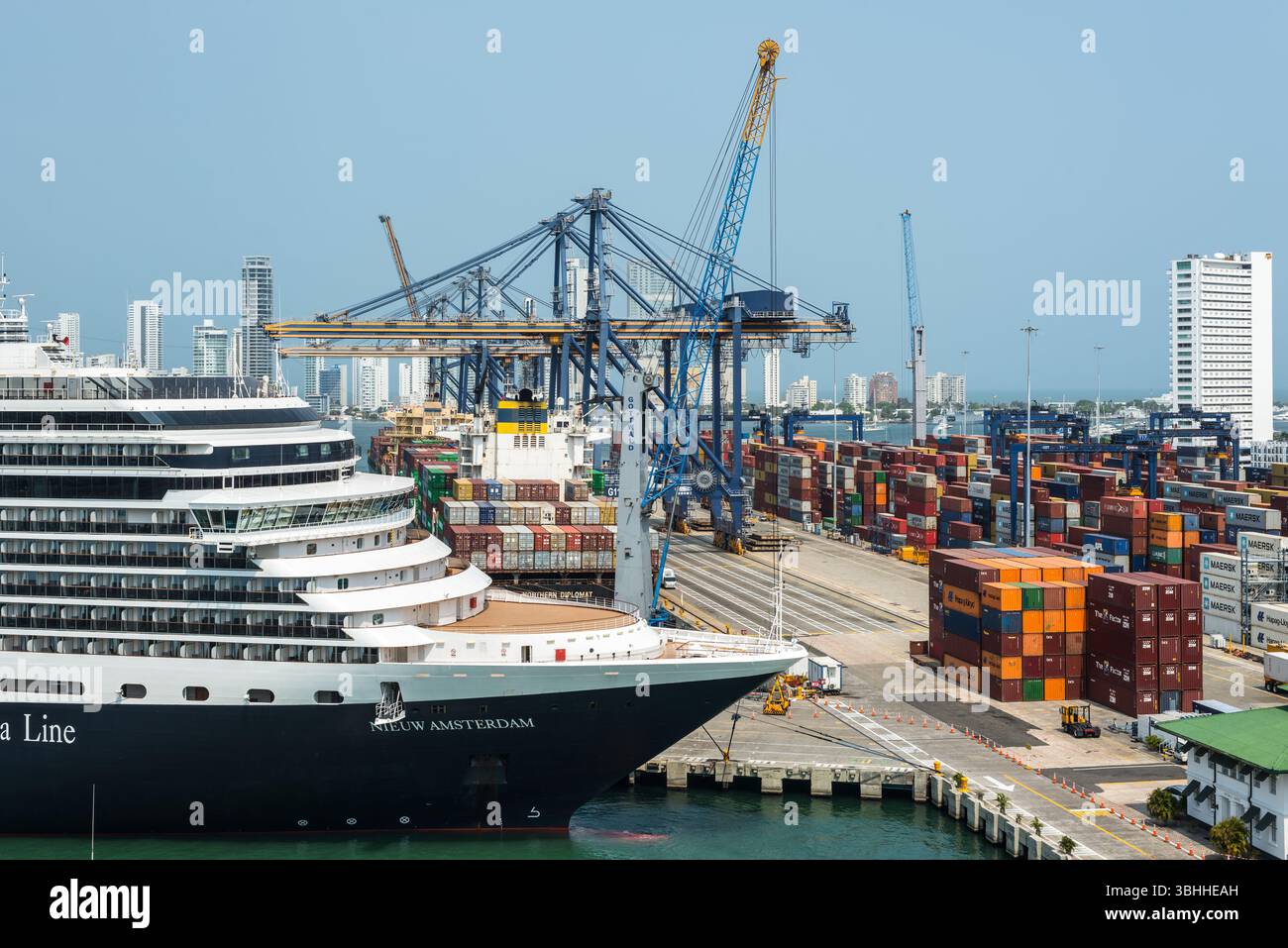 Cartagena, Kolumbien – 12. April 2024: Die Hafenszene mit Kreuzfahrtschiff, Containerschiff, Hafenkränen und Containern steht gegen die BA Stockfoto