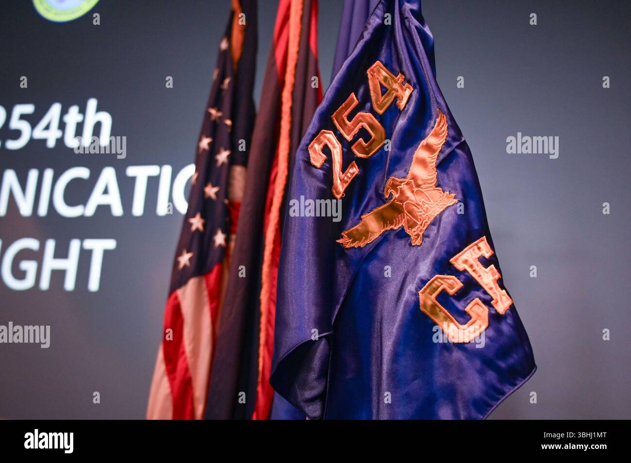 Der brandneue Leitfaden und die Flagge für den 254th Communications Flight (CF) steht unter den Guam- und amerikanischen Flaggen im Meehan Theatre, Andersen Air Force Base, Guam, 7. Juni 2025. Der neu eingerichtete CF 254 kommt zu einer Zeit wachsender Cyberbedrohungen und verstärkter strategischer Schwerpunkte in der indopazifischen Region. (Foto der U.S. Air Force von Airman 1st Class Natasha Ninete). Stockfoto