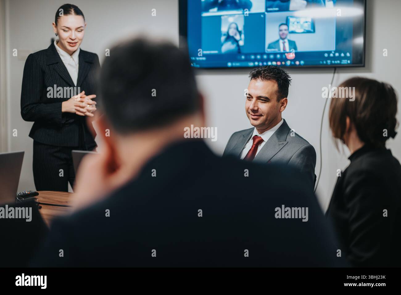 Teamzusammenarbeit in einem hybriden Business-Meeting mit virtuellen Teilnehmern auf dem Bildschirm Stockfoto