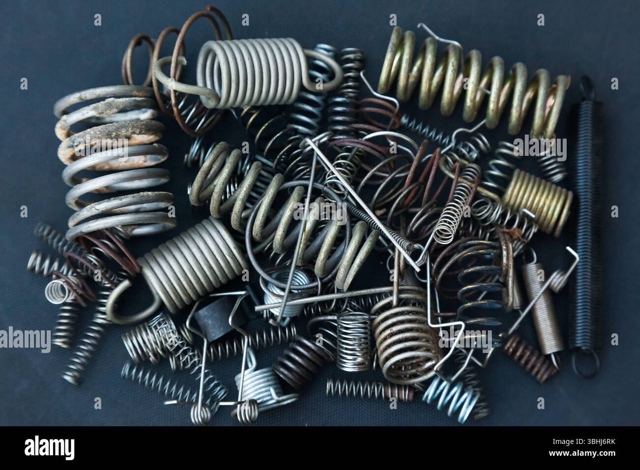 Viele kleine Federn unterschiedlicher Größe liegen auf einem Haufen vor schwarzem Hintergrund. Stockfoto
