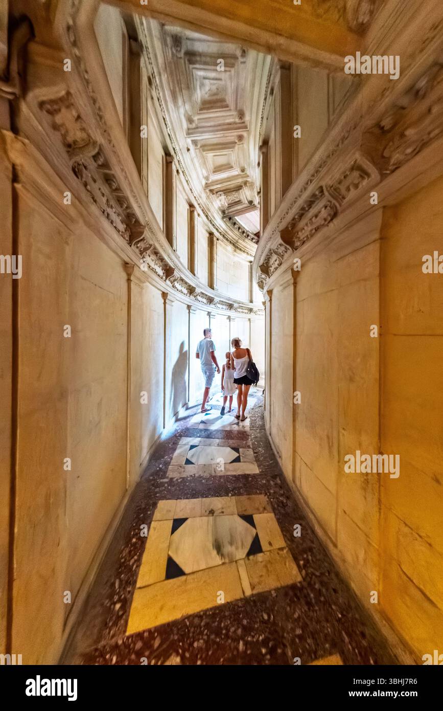 Besucher spazieren durch einen historischen Korridor, der zum Kapitelhaus der Kathedrale von Sevilla führt und wunderschöne architektonische Details zeigt. Stockfoto
