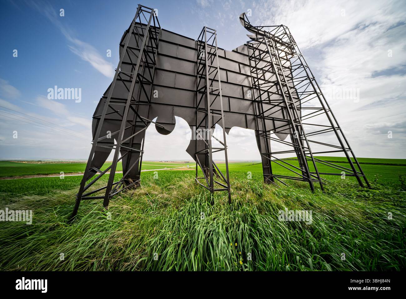 Der ikonische Osborne-Stier steht hoch in den üppig grünen Feldern von Sevilla, Spanien, und zeigt sein tragendes Metallgestell am Himmel. Stockfoto