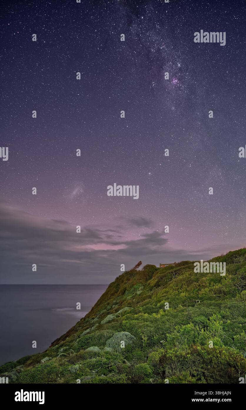 Nachthimmel mit Milchstraße und leichter aurora über Küste und Ozean mit Horizont und Wolken am Point Addis, Victoria, Australien Stockfoto